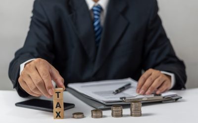 Businessman holding Wood Cube Tax Coin Financial Concept Design with a stack of coins. Business finance, accounting.