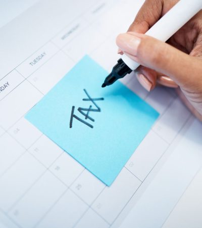 Hand closeup, notes and tax on calendar with finance, law and compliance for money administration. .