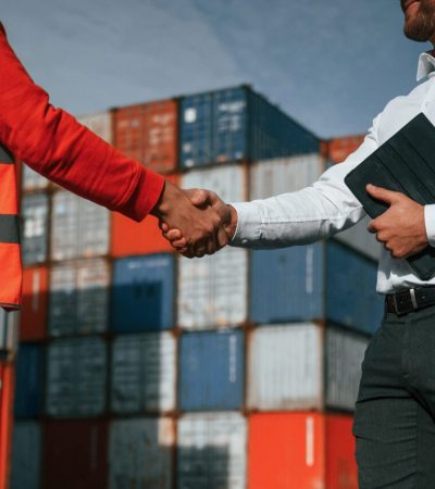 Making handshake. Two male workers is on the location with containers.