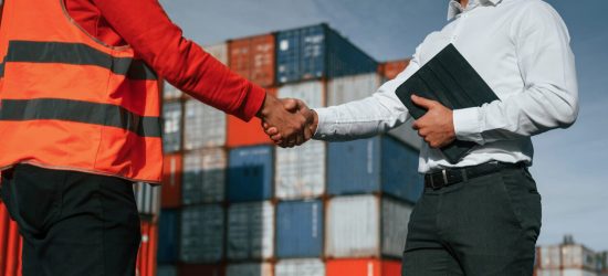 Making handshake. Two male workers is on the location with containers.
