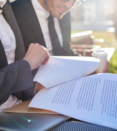 Business papers or contracts held by businesswoman during discussion with colleague at meeting