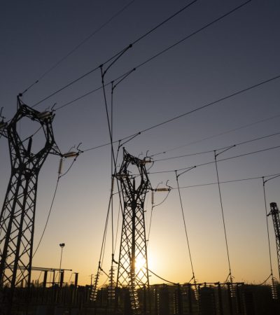 Photographic documentation of the silhouettes of high voltage pylons against a twilight sky with warm and cold tones.