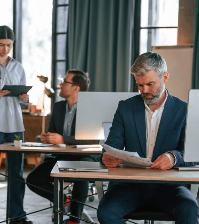 Three people are busy in the office. Group of employees are working together.