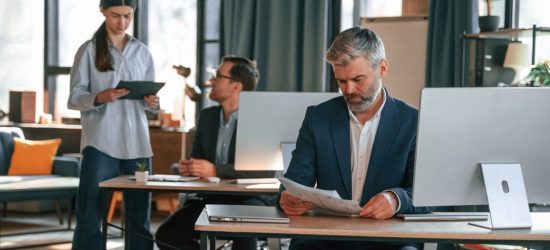 Three people are busy in the office. Group of employees are working together.