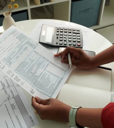 Close-up of African girl checking and calculating her domestic bills at table using calculator
