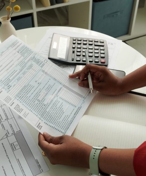Close-up of African girl checking and calculating her domestic bills at table using calculator