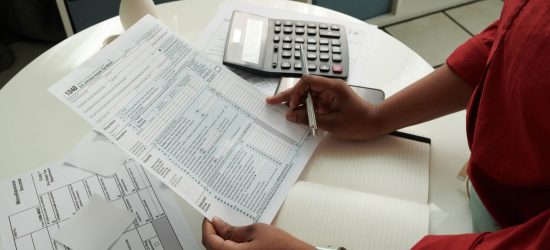 Close-up of African girl checking and calculating her domestic bills at table using calculator